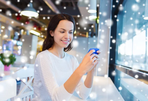 Usmívající se žena s smartphone v kavárně — Stock fotografie
