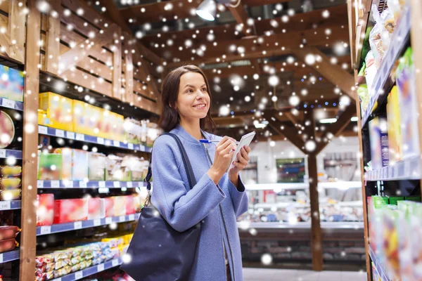 Happy woman with notepad in grocery store — Zdjęcie stockowe