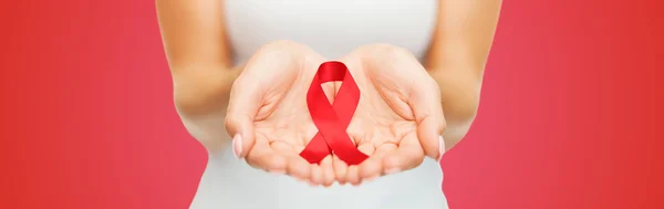 Close up de mãos com fita de conscientização de AIDS vermelho — Fotografia de Stock