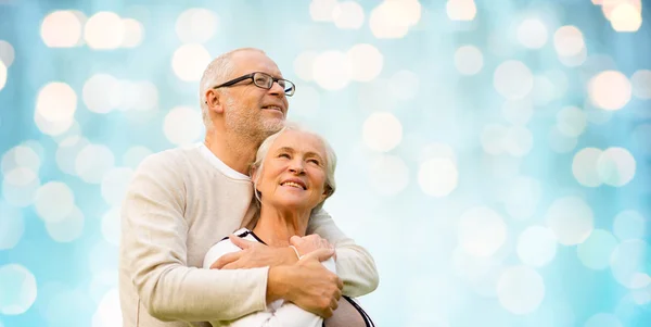 Happy senior couple over blue holidays lights — ストック写真