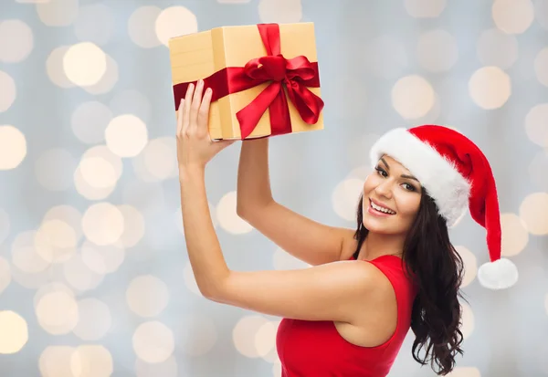 Beautiful woman in santa hat with gift over lights — Stockfoto
