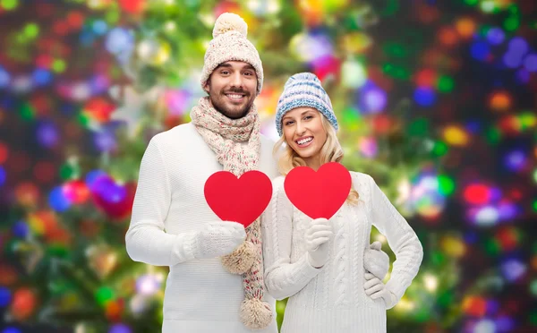 Casal sorridente em roupas de inverno com corações vermelhos — Fotografia de Stock