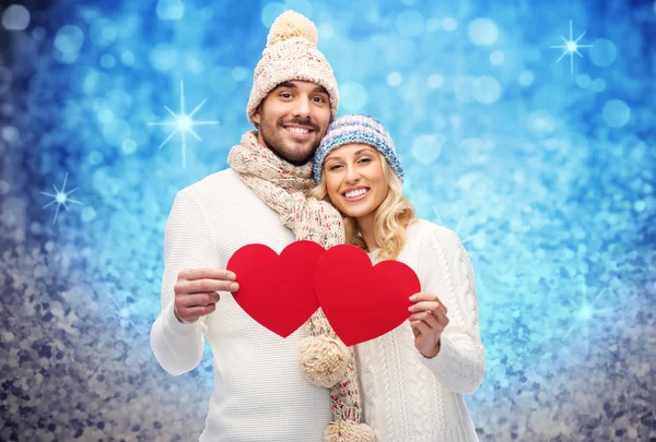 Casal sorridente em roupas de inverno com corações vermelhos — Fotografia de Stock