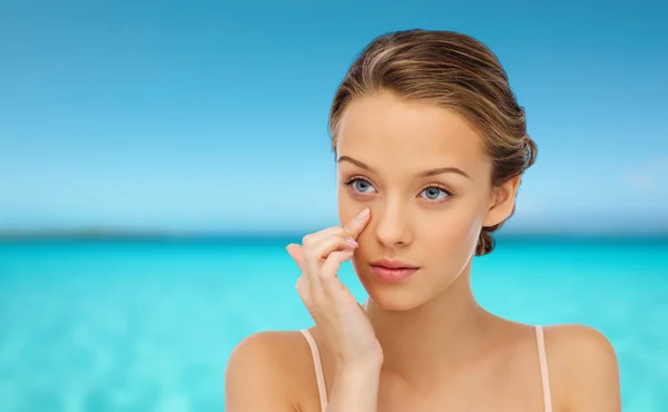 Mujer joven aplicando crema en su cara — Foto de Stock