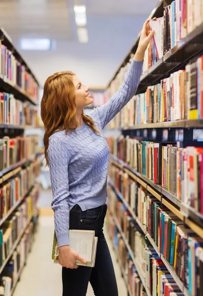 Felice studentessa o donna con libro in biblioteca — Foto Stock