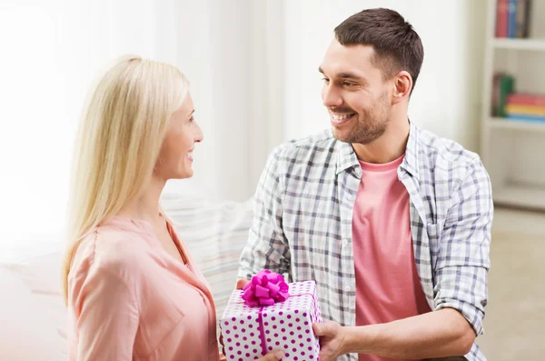 Счастливый мужчина дарит женщине подарочную коробку дома — стоковое фото