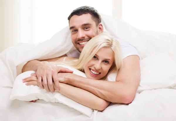 Happy couple lying in bed and hugging at home — Stok fotoğraf