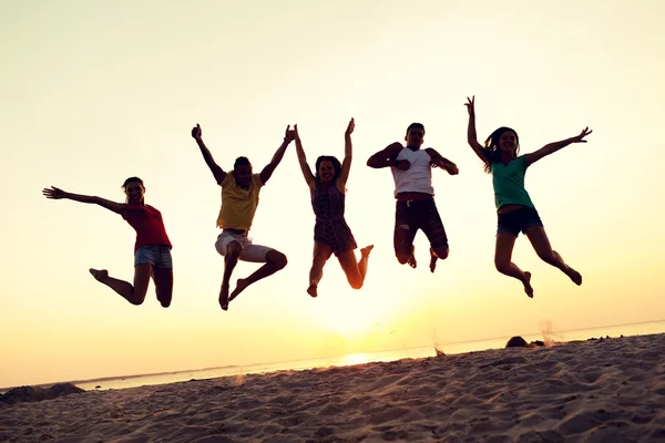 Amigos sonrientes bailando y saltando en la playa —  Fotos de Stock