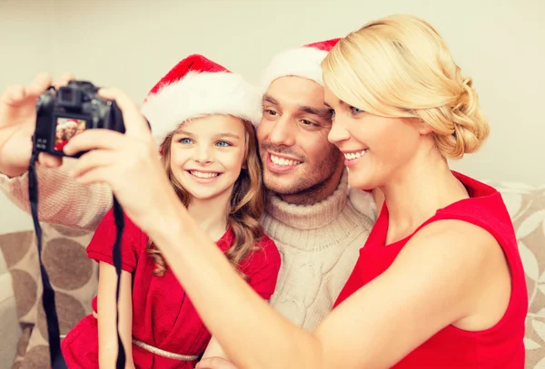 Sonriente familia en santa helper sombreros tomando fotos — Foto de Stock