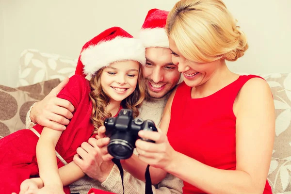 Familie mit Weihnachtsmann-Helferhüten schaut sich Bilder an — Stockfoto