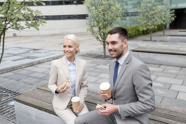 Homens de negócios sorridentes com copos de papel ao ar livre — Fotografia de Stock