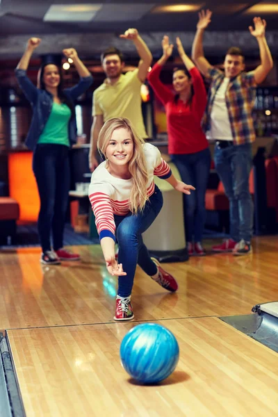 Jeune femme heureuse lançant la balle dans le club de bowling — Photo