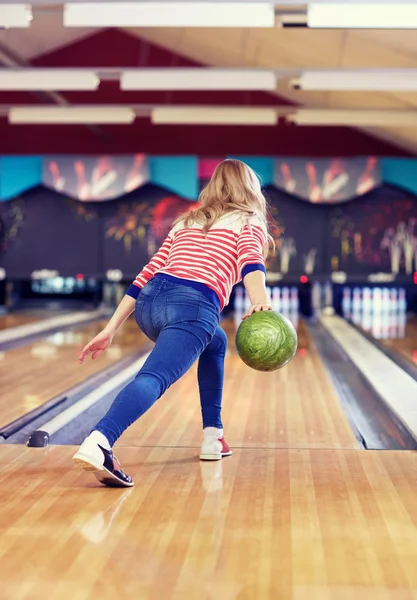 Glückliche junge Frau wirft Ball in Kegelclub — Stockfoto