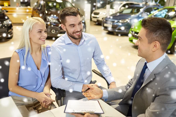 Casal feliz com revendedor de carro em auto show ou salão — Fotografia de Stock