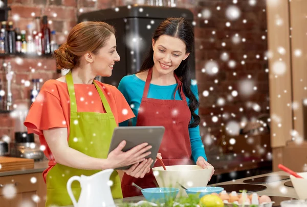 Mulheres felizes com tablet pc cozinhar na cozinha — Fotografia de Stock