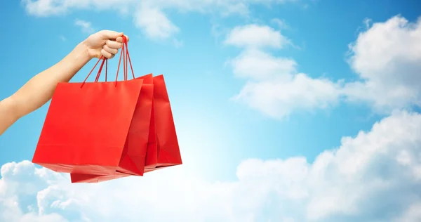 Close up de mão segurando sacos de compras vermelhos — Fotografia de Stock