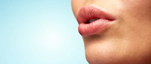Genç kadının dudakları mavi üzerinde yakın çekim — Stok fotoğraf