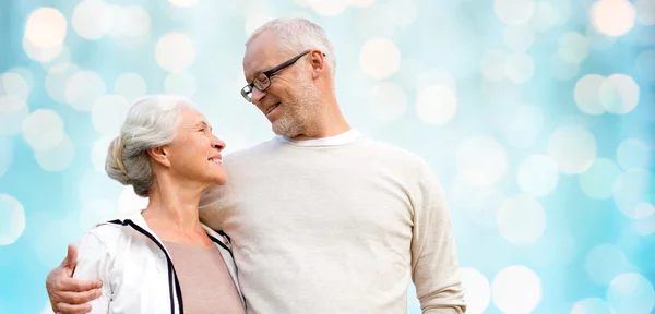 Happy senior couple over blue holidays lights — Stockfoto