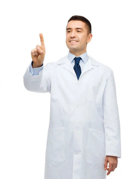 Smiling male doctor in white coat pointing finger — ストック写真