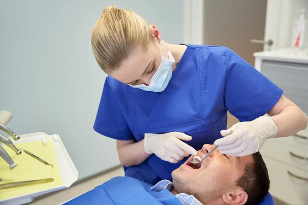 Vrouwelijk tandarts controle mannelijke patiënt tanden — Stockfoto