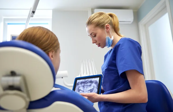 Dentista que muestra rayos X en el comprimido pc a la niña paciente —  Fotos de Stock