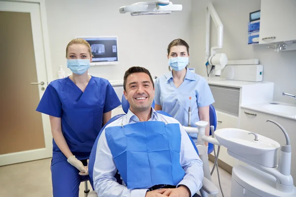 Dentistas felizes do sexo feminino com paciente homem na clínica — Fotografia de Stock