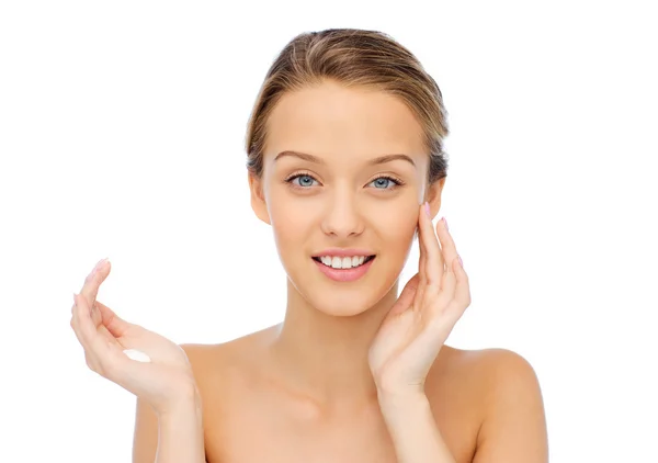 Happy young woman applying cream to her face — Stock Photo, Image