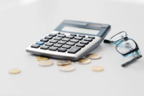 Calculadora, óculos e moedas na tabela do escritório — Fotografia de Stock