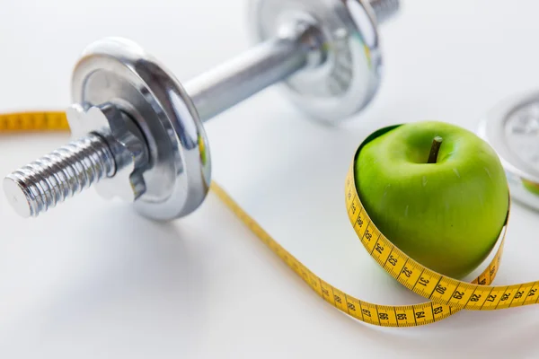 Close-up de haltere e maçã com fita métrica — Fotografia de Stock