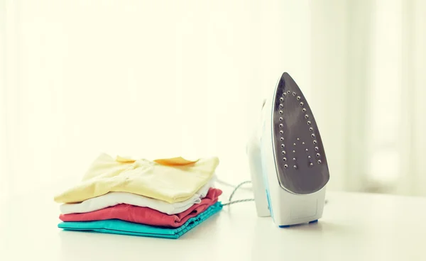 Close up of iron and clothes on table at home — Stock Photo, Image