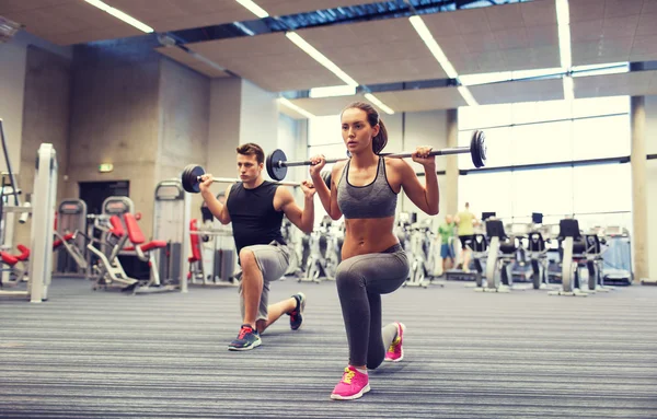 Jovem homem e mulher formação com barbell no ginásio — Fotografia de Stock