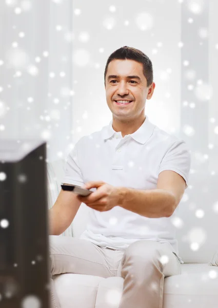 Uomo sorridente con telecomando guardando la tv — Foto Stock