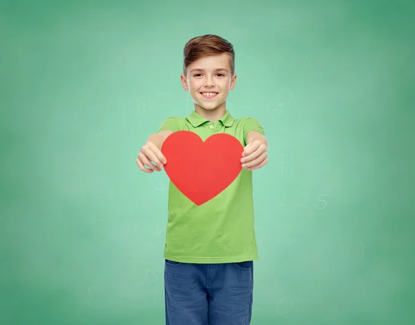 Happy school boy holding red heart shape — Stockfoto
