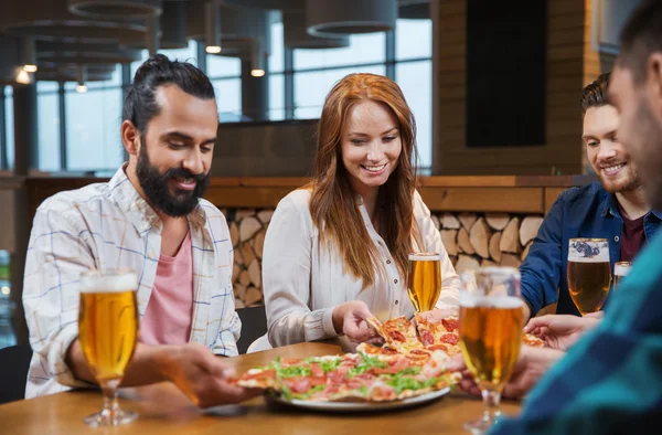 Vrienden eten pizza met bier in restaurant — Stockfoto