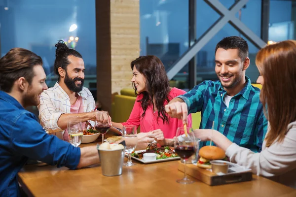 Amigos comiendo y degustando comida en el restaurante — Foto de Stock