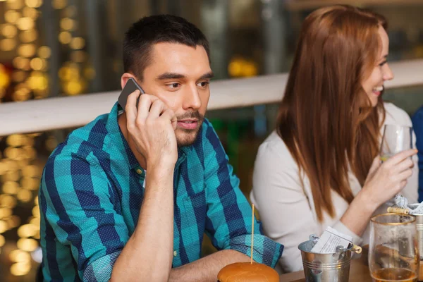 Człowiek z smartphone i przyjaciółmi w restauracji — Zdjęcie stockowe