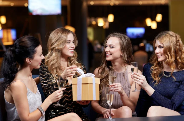 Mujeres felices con champán y regalo en el club nocturno —  Fotos de Stock