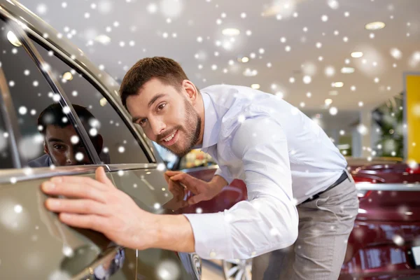 Счастливый человек трогает машину в автосалоне или салоне — стоковое фото