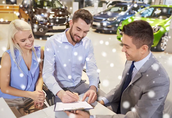 Casal feliz com revendedor de carro em auto show ou salão — Fotografia de Stock