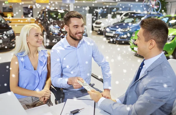 Casal feliz com dinheiro comprando carro de revendedor — Fotografia de Stock