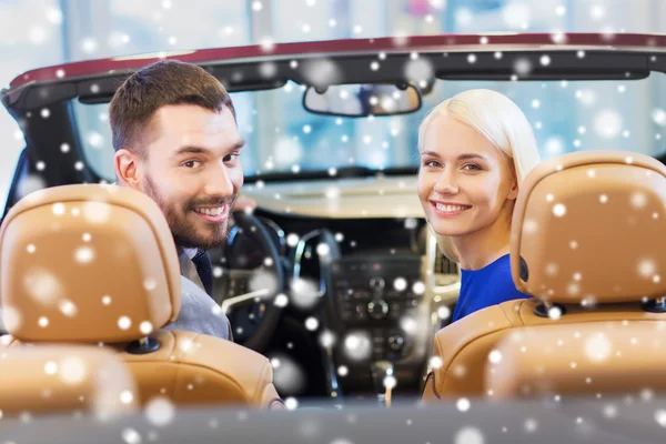 happy couple sitting in car at auto show or salon