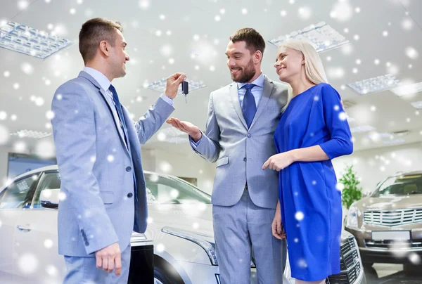 Casal feliz com revendedor de carro em auto show ou salão — Fotografia de Stock