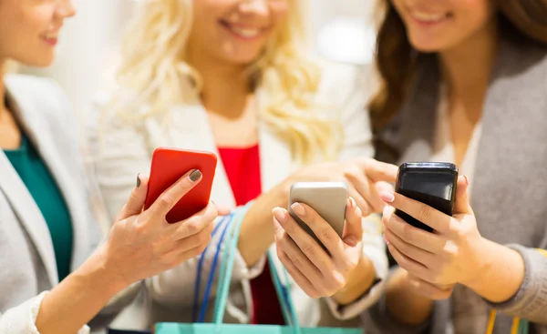 Mulheres felizes com smartphones e sacos de compras — Fotografia de Stock