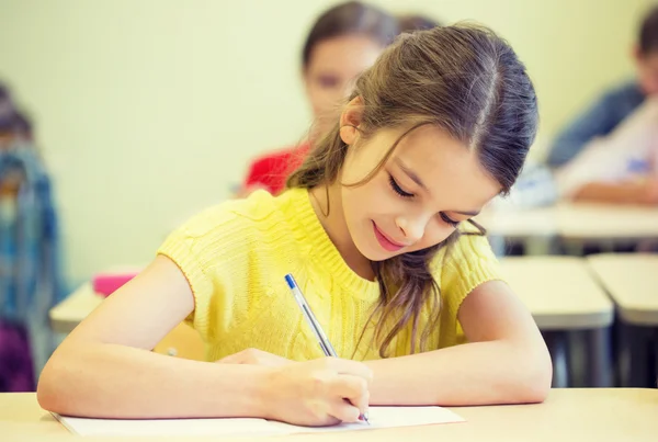 Group of school kids writing test in classroom Stock Picture