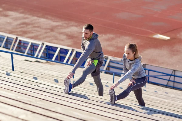 Paar streckt Bein auf Tribüne des Stadions — Stockfoto