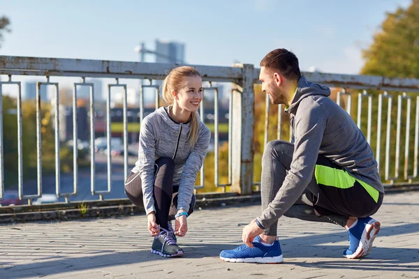 Smiling couple tying shoelaces outdoors — Stock Photo, Image