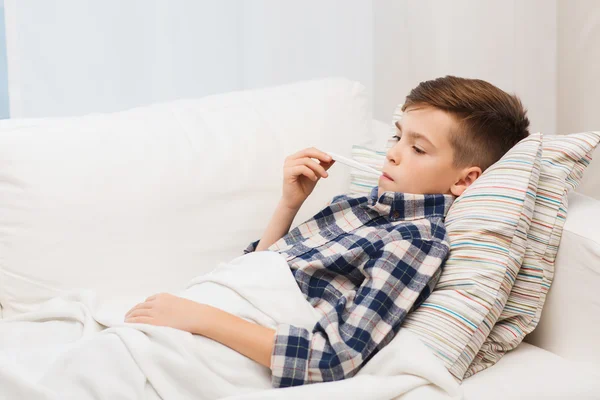 Niño enfermo con gripe y termómetro en casa — Foto de Stock