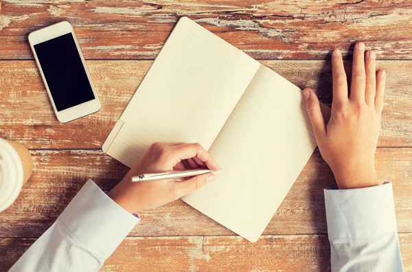 Close up of hands with notebook and smartphone — Stock Photo, Image