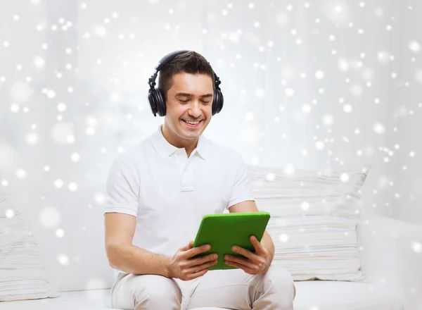 Hombre sonriente con tablet PC y auriculares en casa — Foto de Stock