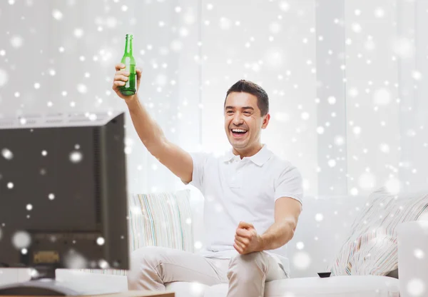 Sorrindo homem assistindo tv e bebendo cerveja em casa — Fotografia de Stock